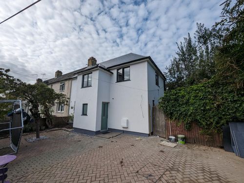 Completed house exterior with fresh white render and new windows